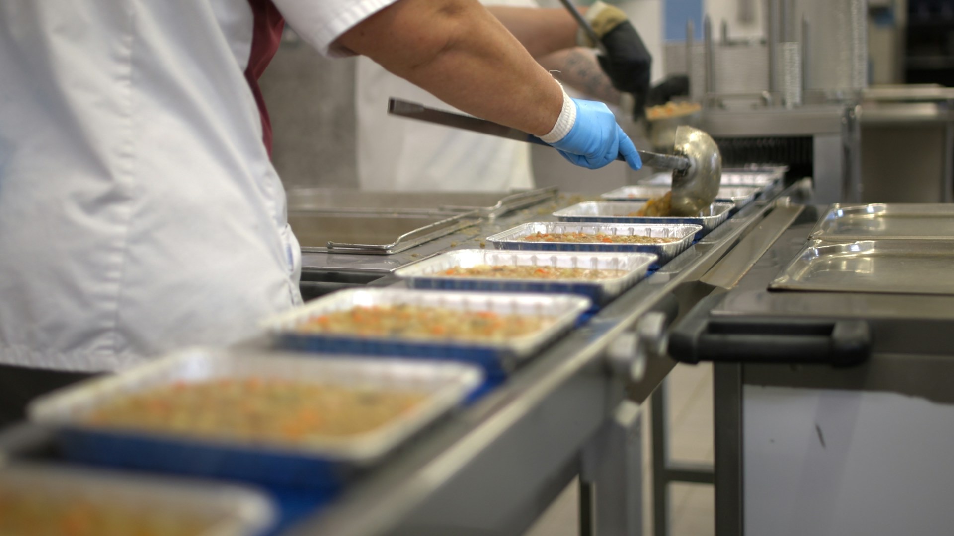 Worker filling food trays on a production line